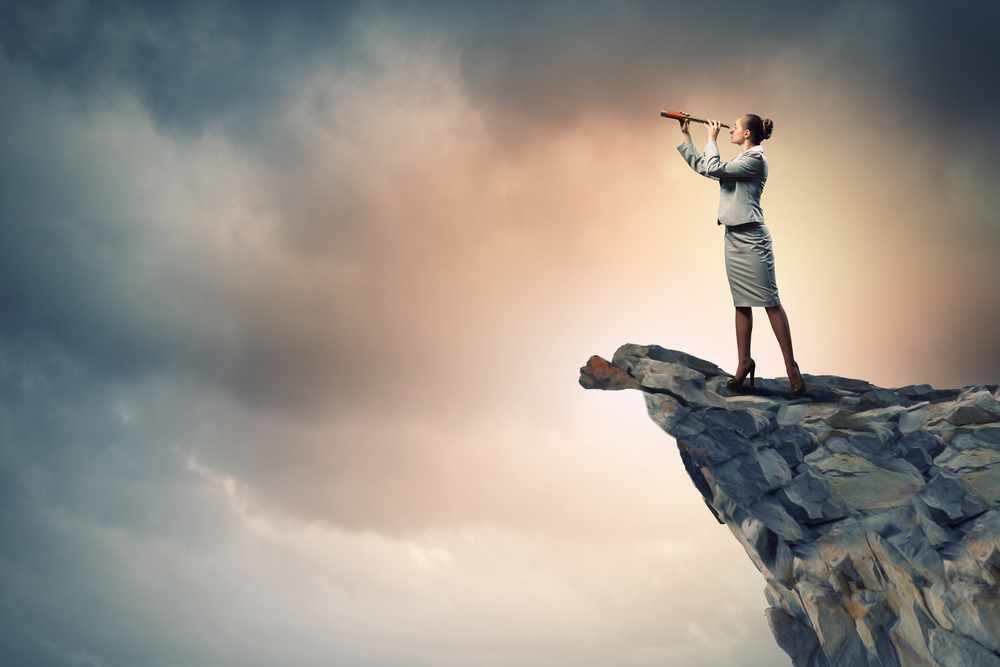 Image of businesswoman looking in telescope standing a top of rock
